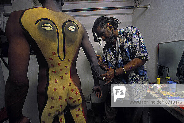 A Cuban artist puts the finishing touches of body paint on a nude model.