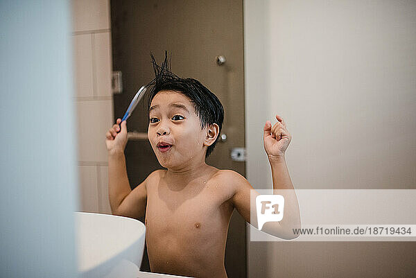 Asian boy combing hair in front of mirror