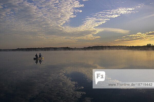 A couple bass fishing at dawn with fog rising off the water in southern Illinois.