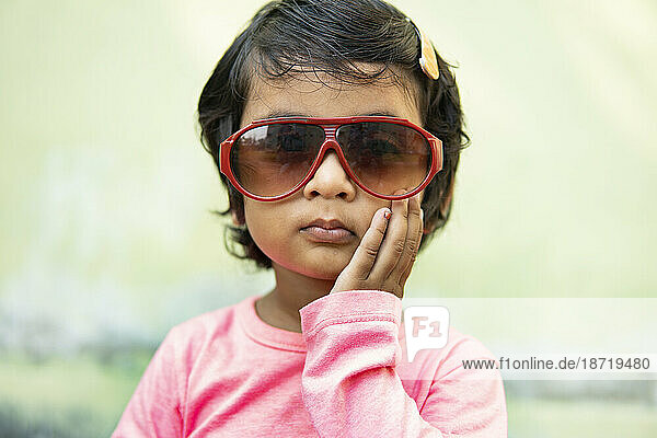 Cute little girl wearing fashionable sunglasses and making fun