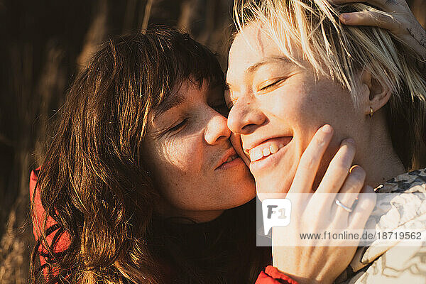 sweet queer couple cuddle in sunshine on winter hike in europe