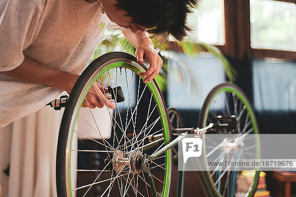 bike mechanic fixes wheel of green vintage bike in wooden studio
