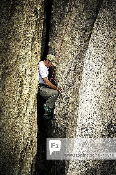 A man climbs up a wide crack in Joshua Tree.