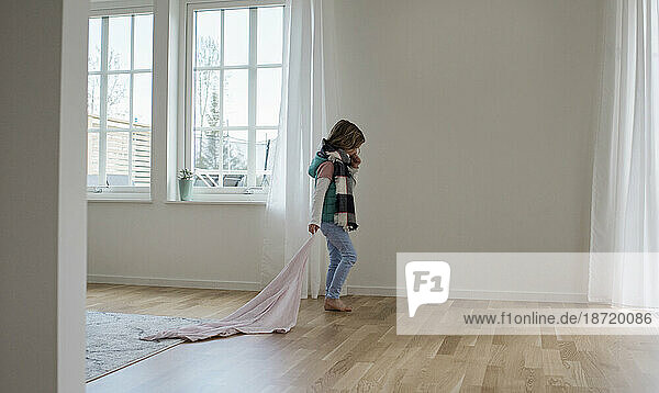 young girl walking through her home with her blanket