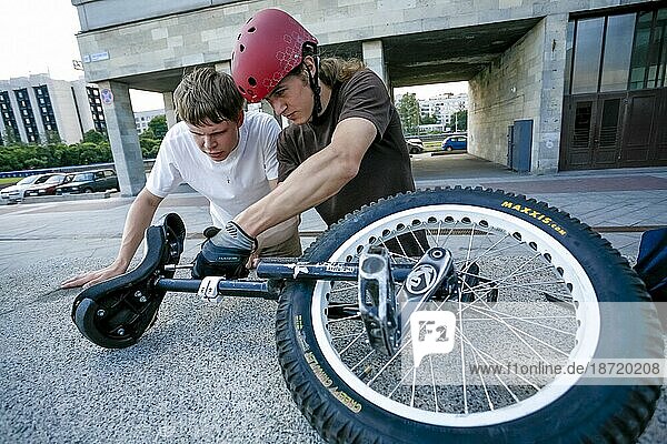 Two Boys Tune Up A Unicycle Before Performing Tricks