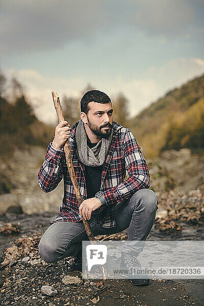 handsome man in nature  holding wooden stick