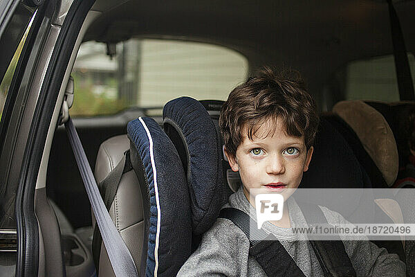 top half of a small child with direct gaze sitting in carseat in car