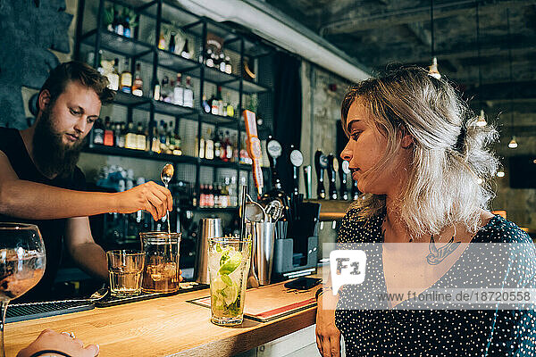 Girl And Barman In A Cocktail Bar.
