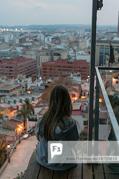 Young woman looking at city lights from a rooftop