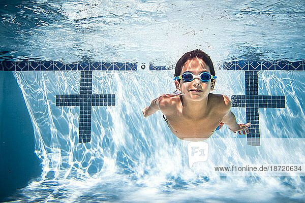 Underwater photograph of boy swimming in goggles.