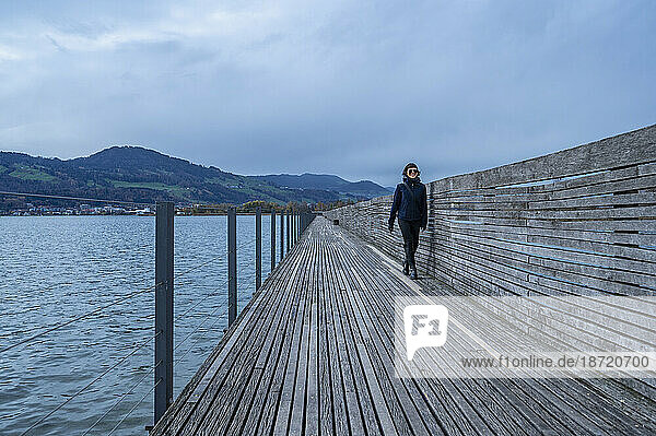 woman walking on boardwalk over lake close to Zurich