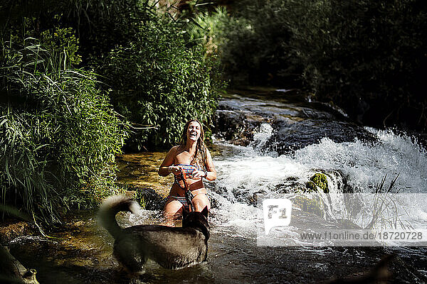 Blond woman bathing in nice river with siberian husky dog.