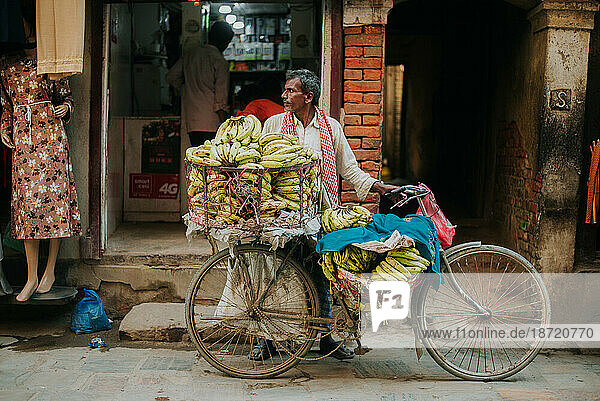 Man selling bananas on street off of bicycle cart in Asia