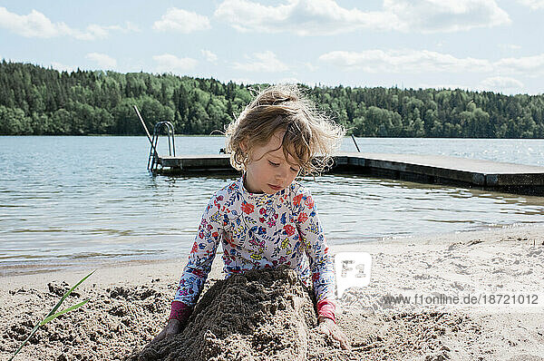 young girl playing in the sand at the beach