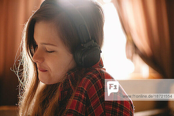 Happy teenage girl with eyes closed listening music on headphones