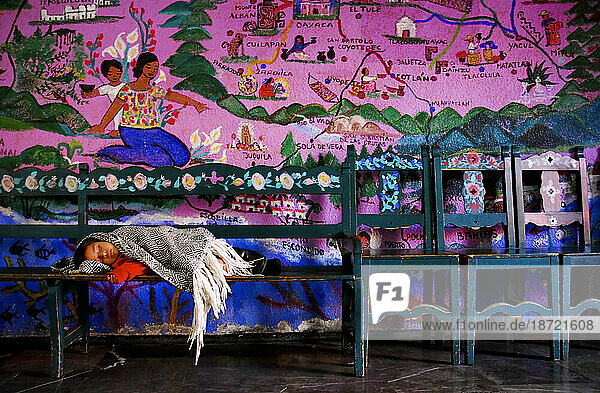 A baby sleeps under a colorful mural in Oaxaca  Mexico.
