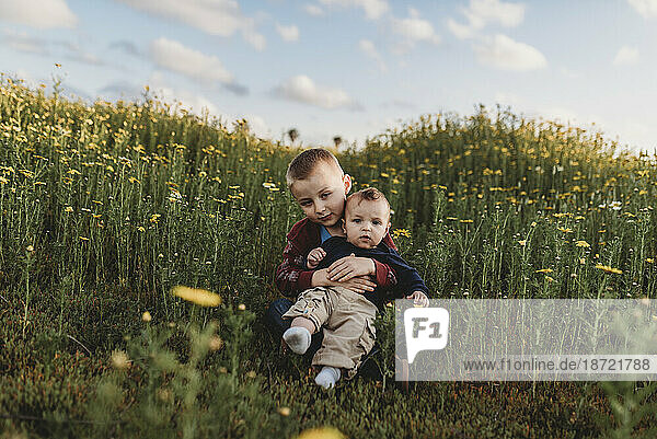 Portrait of brothers sitting in a field of flowers smiling