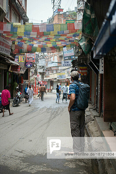 Young man with backpack standing in street of Asia with Himalayan flag