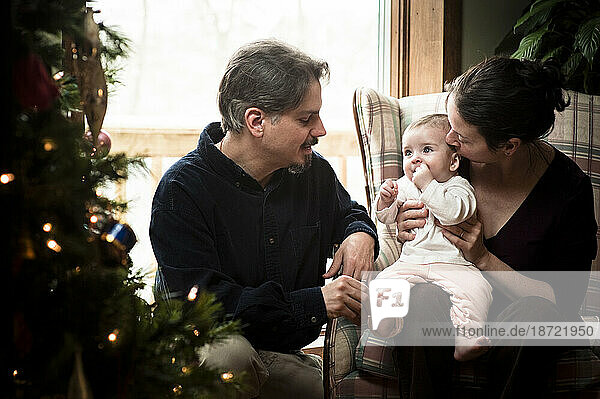 A portrait of a baby's first Christmas with her parents.