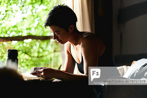 healthy asian woman sits inside her wooden home by window light green