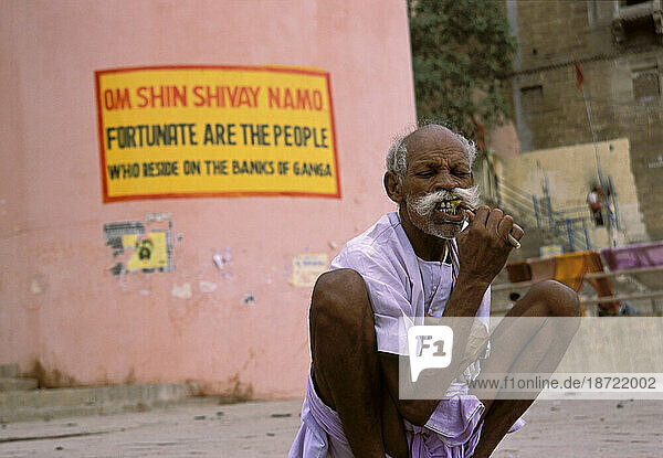 A man brushes his teeth with a licorice branch on the banks of the holy Ganges river in Varanasi  India.