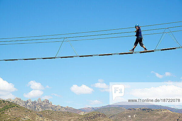 Crossing a Tibetan bridge during via ferrata climbing in Spain