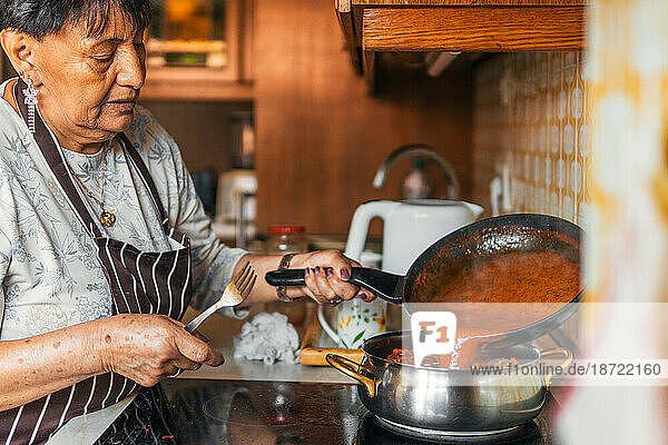 older latin american woman immigrant mixing sauce cooking meatloaf