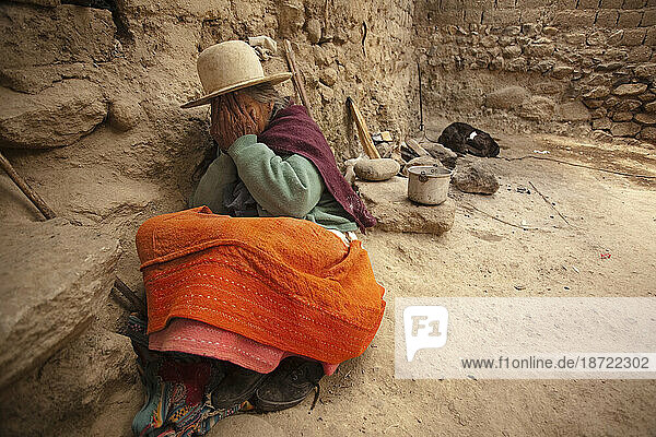 old Peruvian woman hides from the camera while sitting in the ground. Huaraz  Peru.