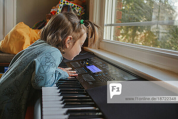 a little girl curiously explores the keys on a piano keyboard