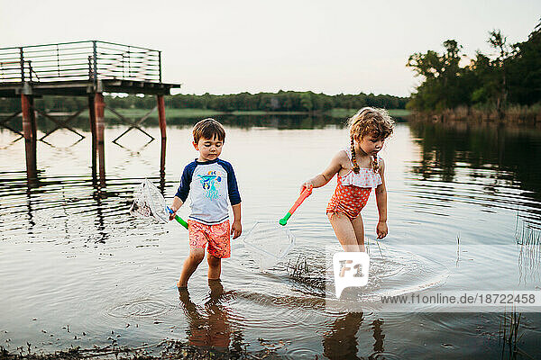 Young boy and girl swimming and catching fish at lake