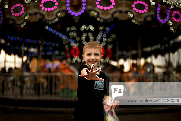 BOY AT THE CARNIVAL WITH STICKY FINGERS FROM COTTON CANDY
