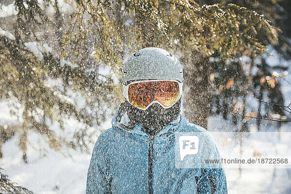 Woman in ski goggles and helmet in backlit snow scene in New Hampshire