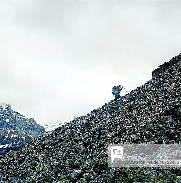 A woman hikes up a rocky slope.