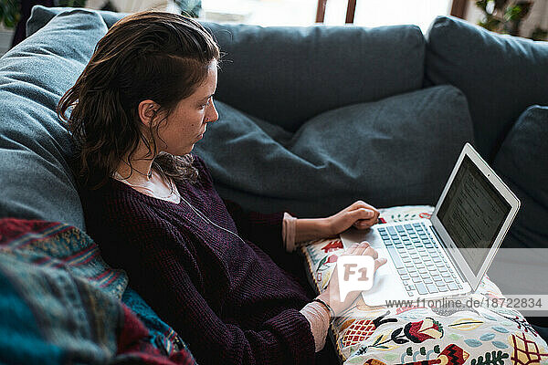 relaxed woman works from home on computer on sofa