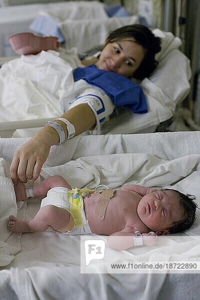 A mother laying next to her newborn in a hospital
