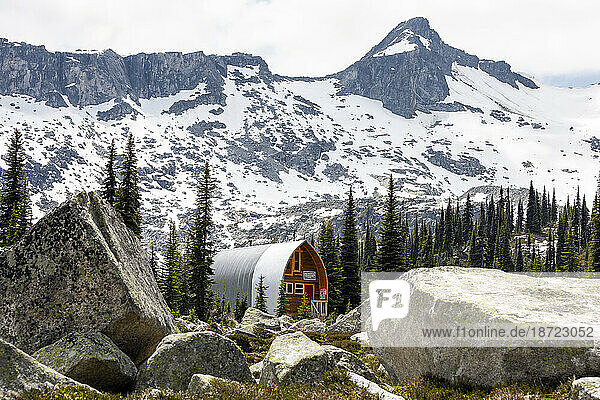 Scenic view of alpine cabin in grassy mountain meadow in Canada.