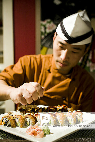 A chef prepares a plate of sushi.