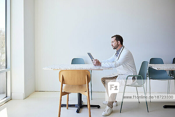 Side view of male doctor using tablet PC while sitting on chair