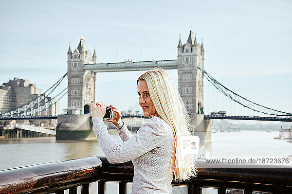 Attractive woman taking picture of Tower Bridge