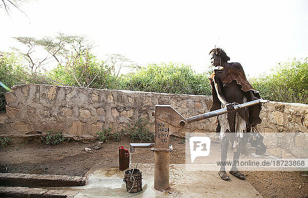 An older woman pumps water from a well in the rural Hamer village of southern Ethiopia.