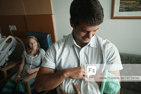 A father holds his new born daughter the day after she was born.