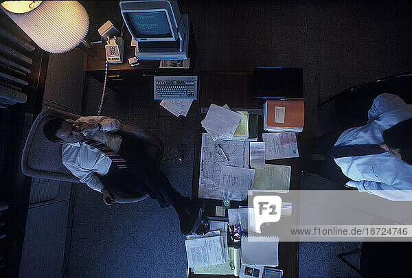 View from above of the former chairman of a large financial company speaking on the phone in his office.