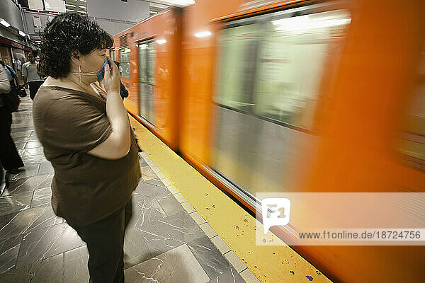A woman covers her mouth with her hand and a mask when the metro (subway) arrives in the station during the swine flu epidemic i