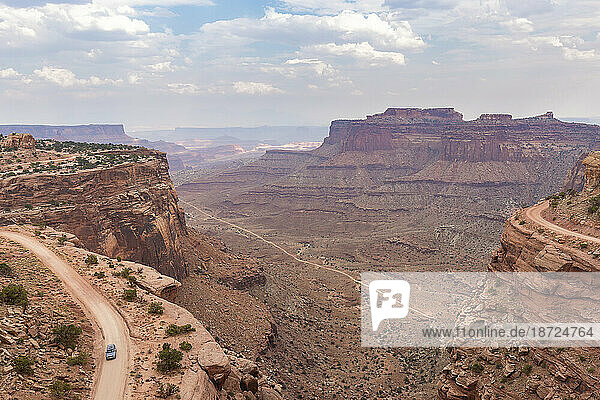 View of a car travesing the White rim road from Shafer canyon tr