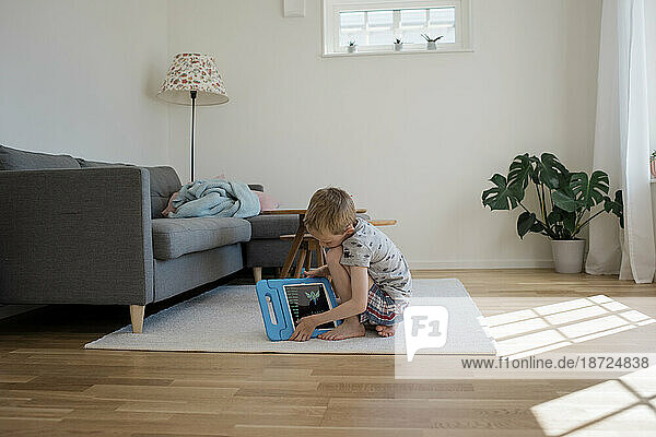 young blonde boy playing with an iPad at home