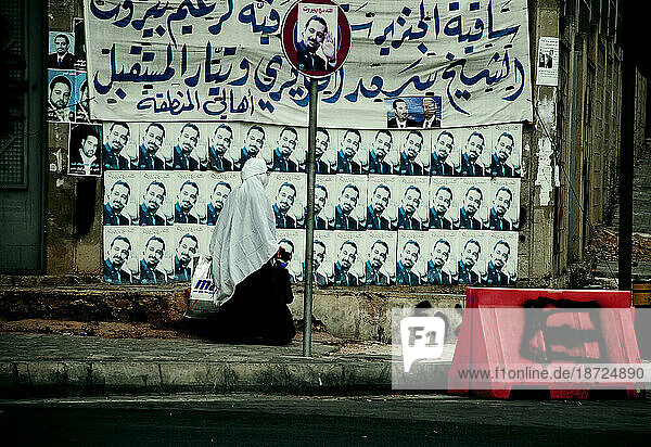 Muslim woman walking in front of political advertising in Beirut  Lebanon.