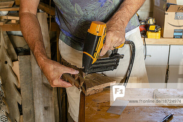 Above view of a men using a hand drill in his woodworking shop