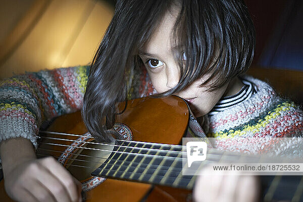 Young Asian girl playing acoustic guitar and writing a song