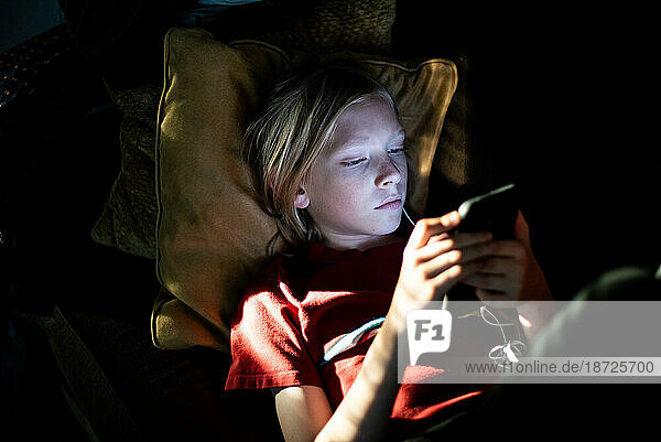 Young boy looking at smart phone in the dark