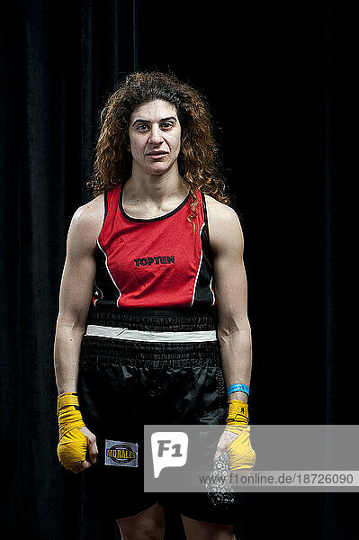 A female boxer with long auburn hair and yellow hands wraps stands in for a portrait minutes after being defeated in her semi-final round at the Canadian Amateur Boxing Championshi